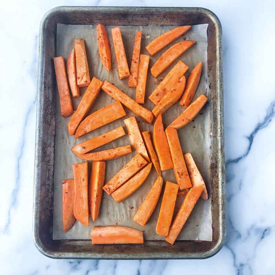 Seasoned oil-free oven toasted Sweet potato fries on a sheet pan.