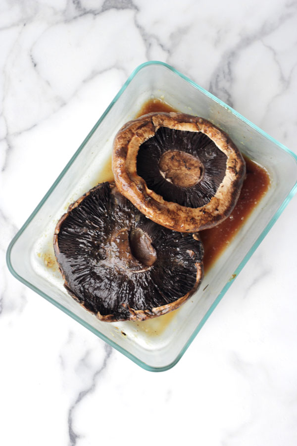 Portobello mushrooms in balsamic marinade in a glass dish.