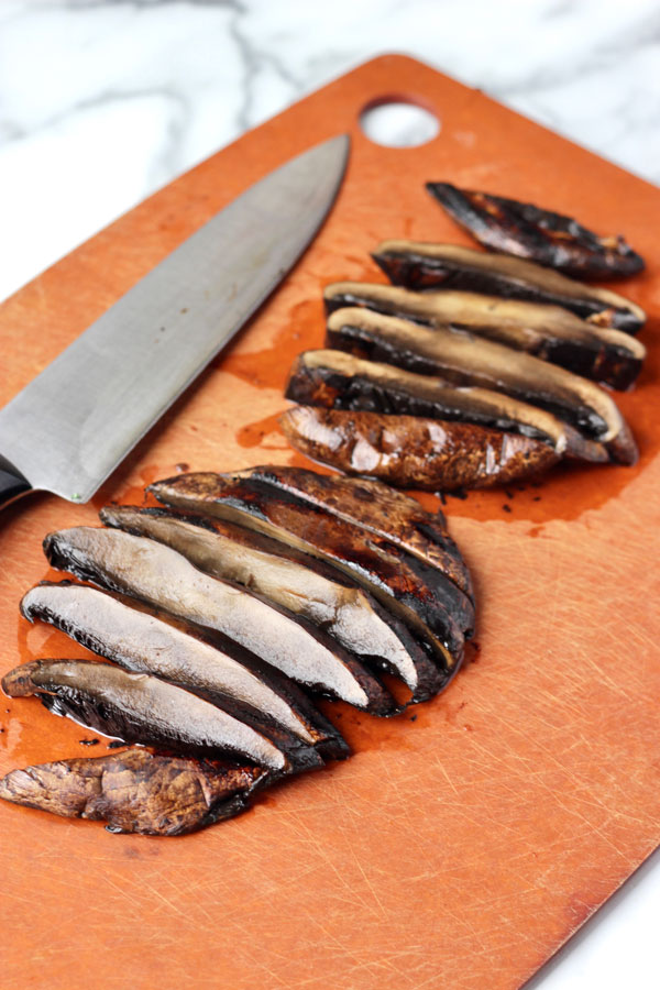 Sliced grilled portobello mushrooms on a cutting board.