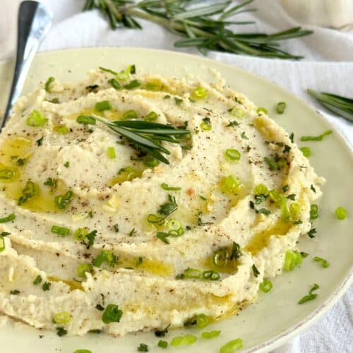 Creamy mashed cauliflower with herb garnish.