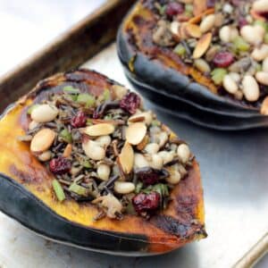 Two halves of stuffed acorn squash on a baking tray.