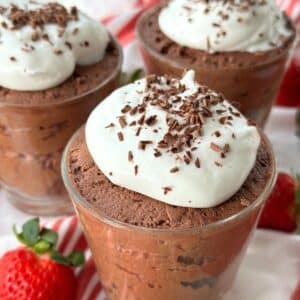 3 ingredient vegan chocolate mousse with whipped cream on top and chocolate shavings in 3 small glass serving containers.