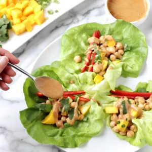 Chickpea lettuce wraps with peanut sauce and mango on a plate.