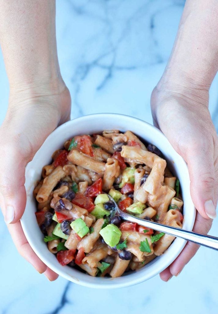 Hands holding taco pasta in white bowl