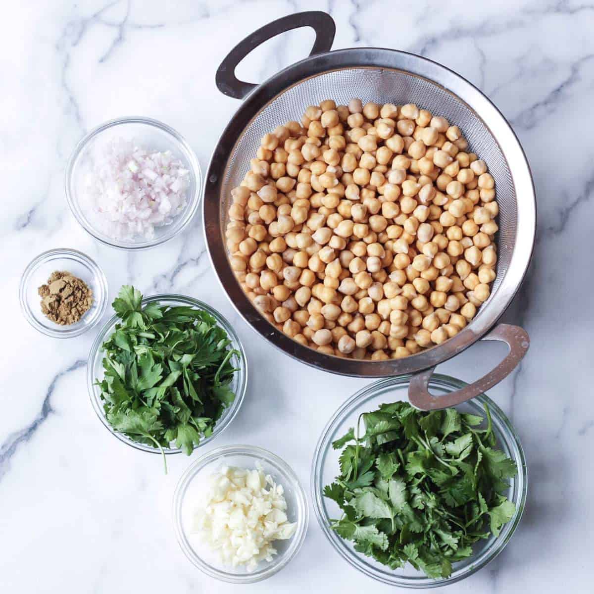 Ingredients to make baked falafels: chickpeas, shallots, cloves, parsley, cilantro, and spices.