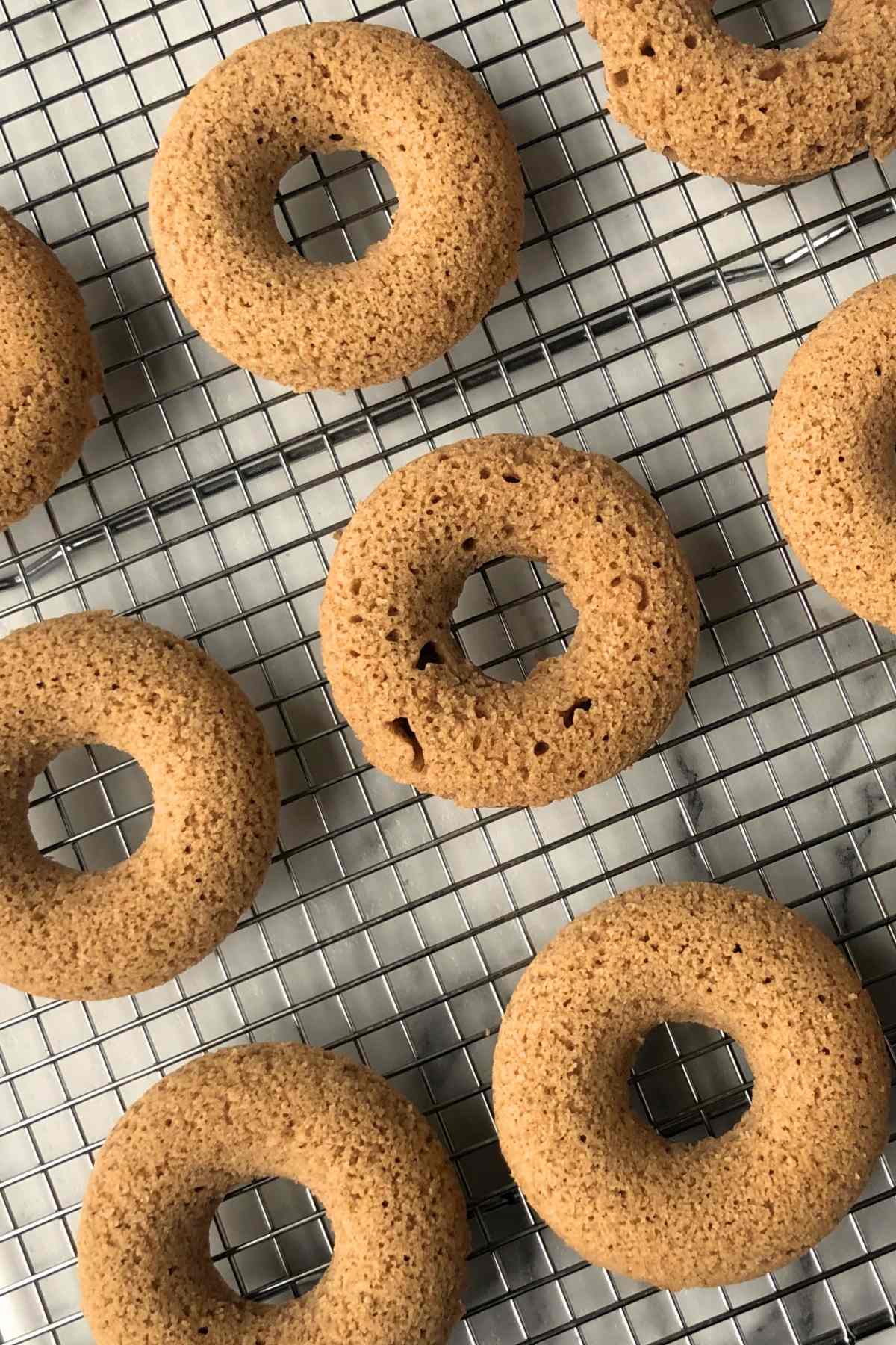 Baked apple cider donuts on a wire rack to cool.