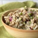 Wooden bowl filled with vegan chicken salad using soy curls on top of a green napkin.