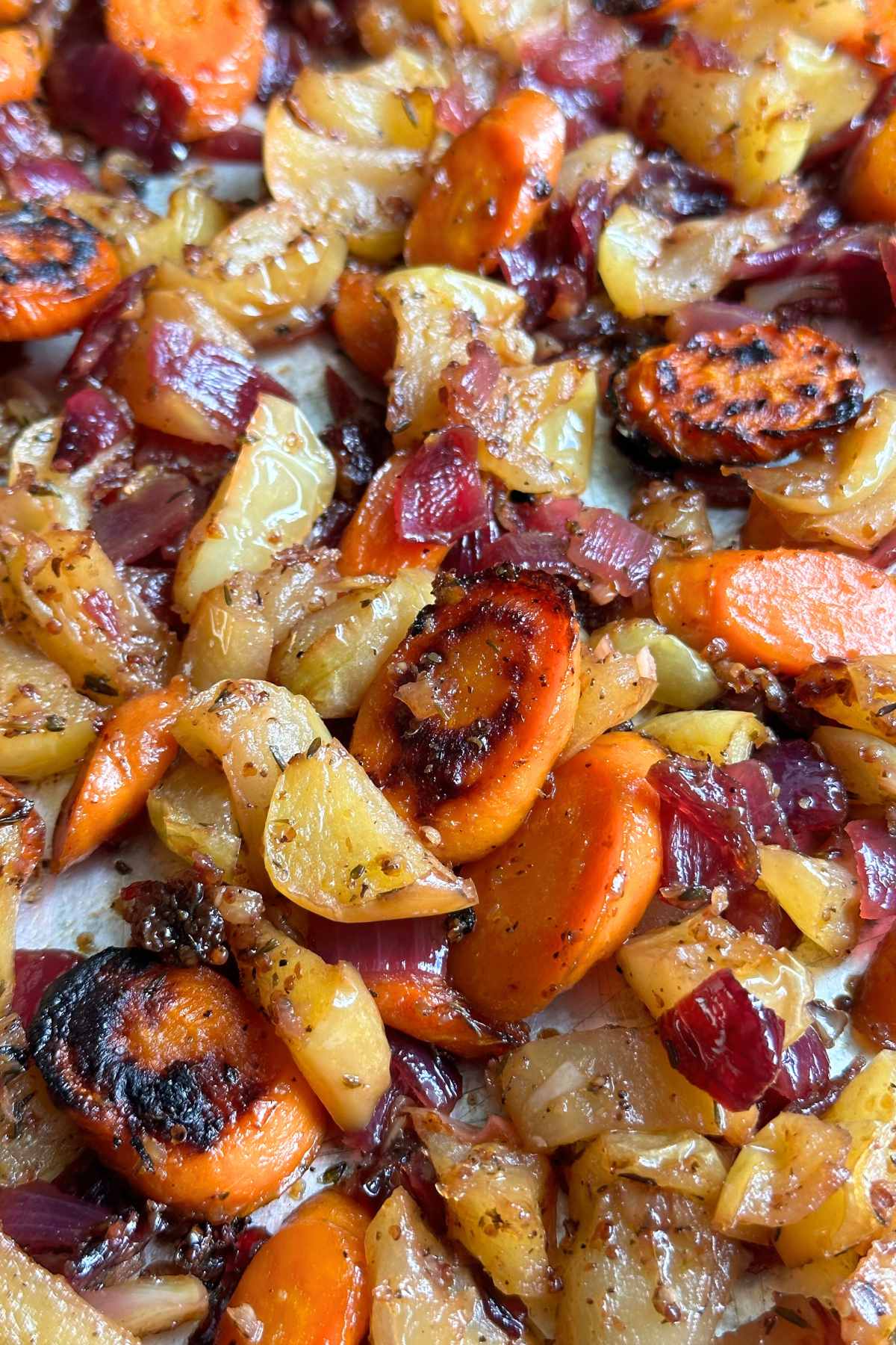 Maple dijon roasted carrots and apples with red onion and garlic on a sheet pan.