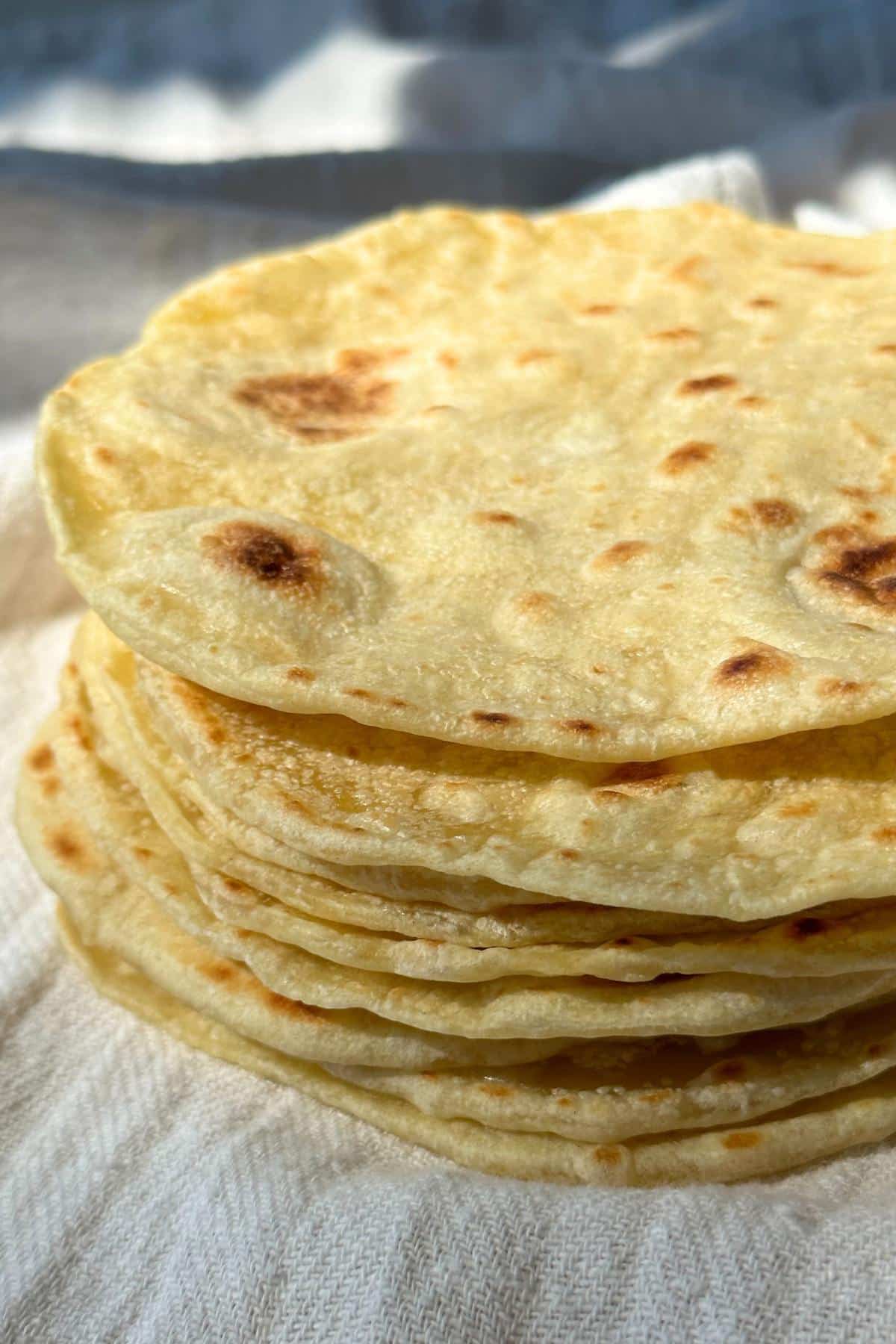 Tortillas stacked on top of a white cloth napkin.