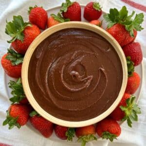 Brownie batter hummus in a bowl surrounded by strawberries.