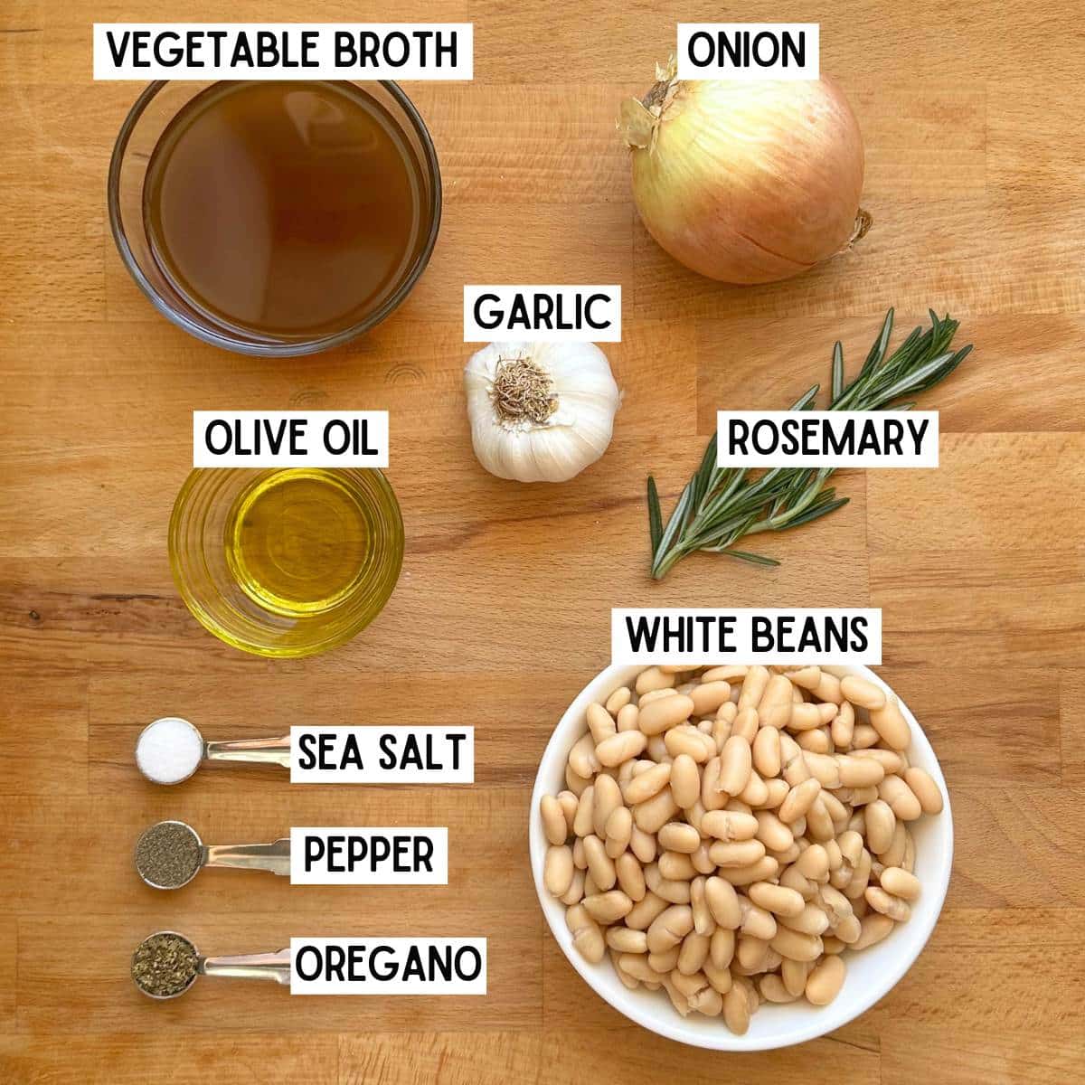 Ingredients needed to make Zoe's white bean recipe with corresponding labels: vegetable broth, onion, garlic, olive oil, rosemary, white beans, sea salt, pepper, and oregano.