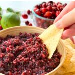 Chip dipped into bowl of homemade cranberry jalapeño salsa.