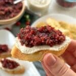 Vegan cranberry crostini with more crostini and crostini ingredients in the background.