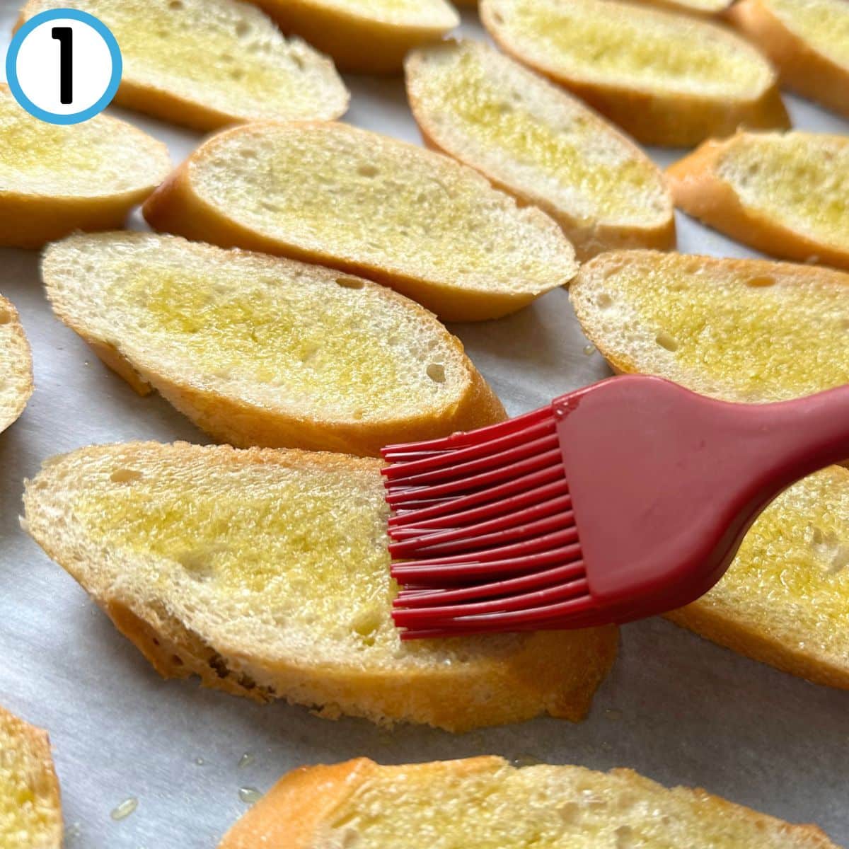 Brushing sliced bread with olive oil using a pastry brush.