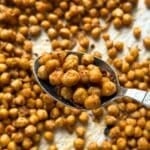 Roasted sriracha lime chickpeas on a serving spoon with more in the background on a pan.