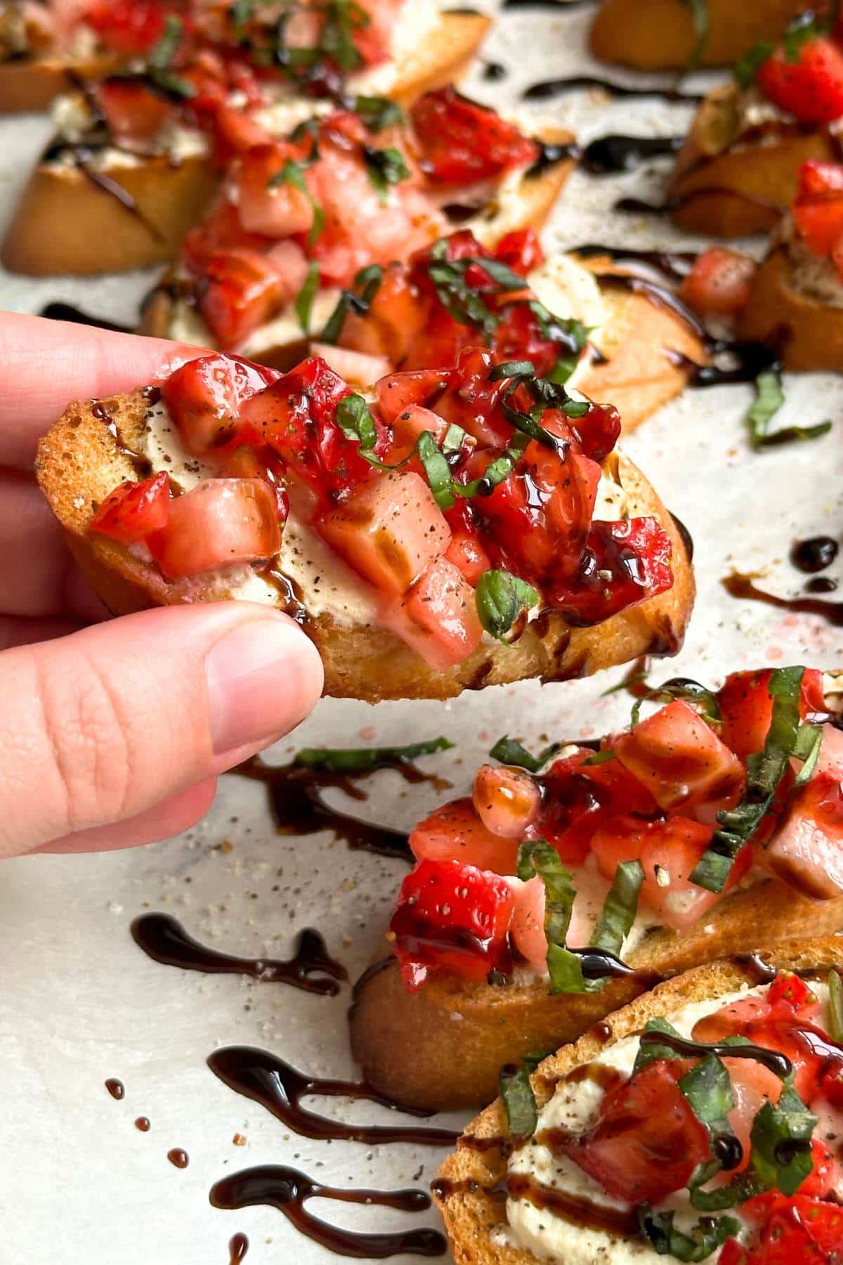 Strawberry balsamic Crostini held up form a tray of crostini.