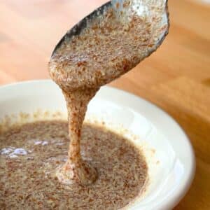 Flax egg dripping from a spoon into a bowl of flax egg.