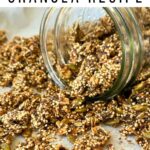 Big clusters of crunchy quinoa granola spilling out of a glass mason jar.
