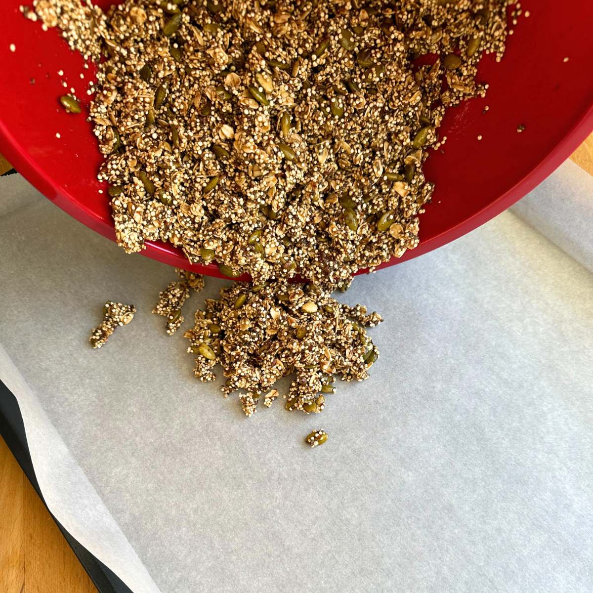 Pouring granola mixture onto a baking sheet with parchment paper.