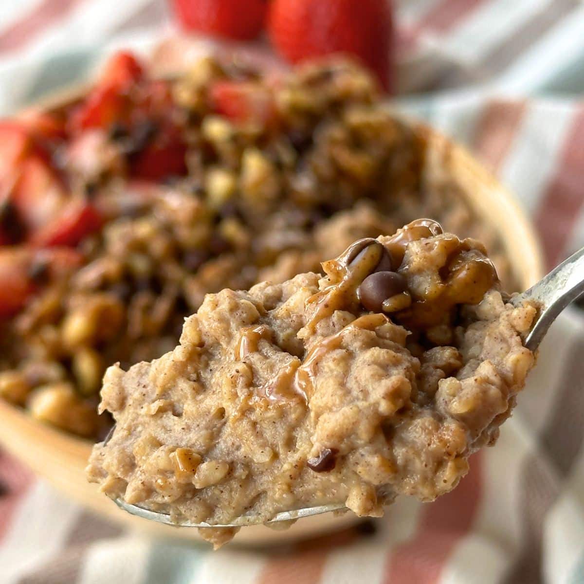 Protein steel cut oatmeal on a spoon with chocolate chips and almond butter. More oatmeal is in the background.