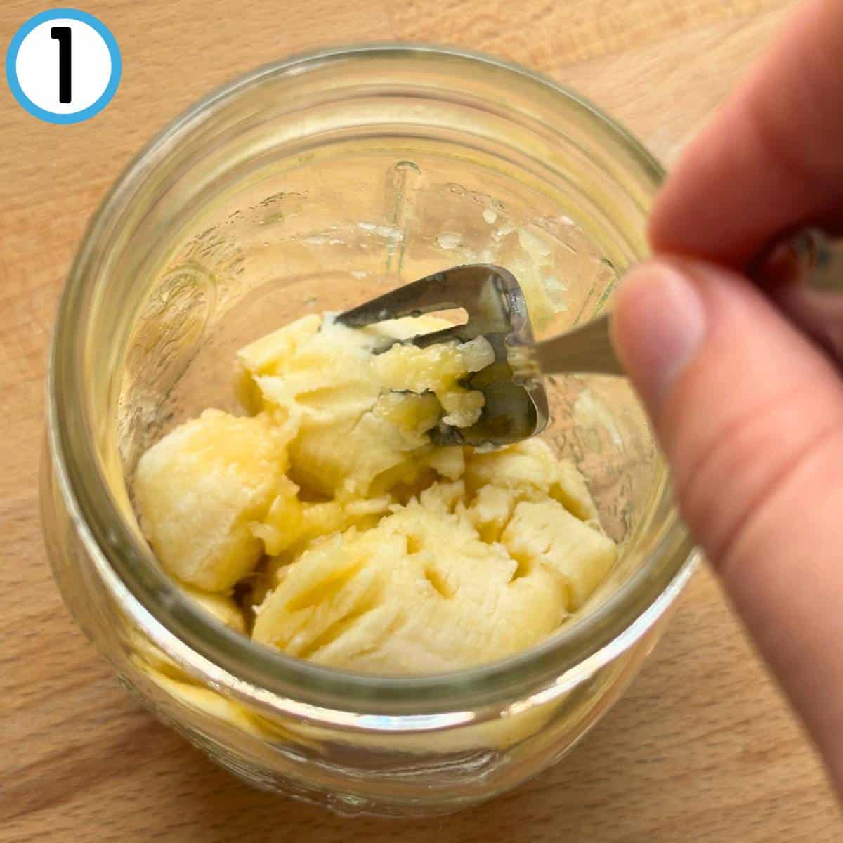 Overhead photo of mashing a banana with a fork.