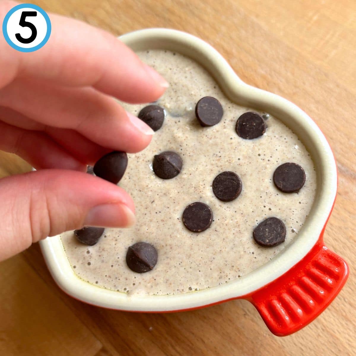 Adding chocolate chips on top of oatmeal.