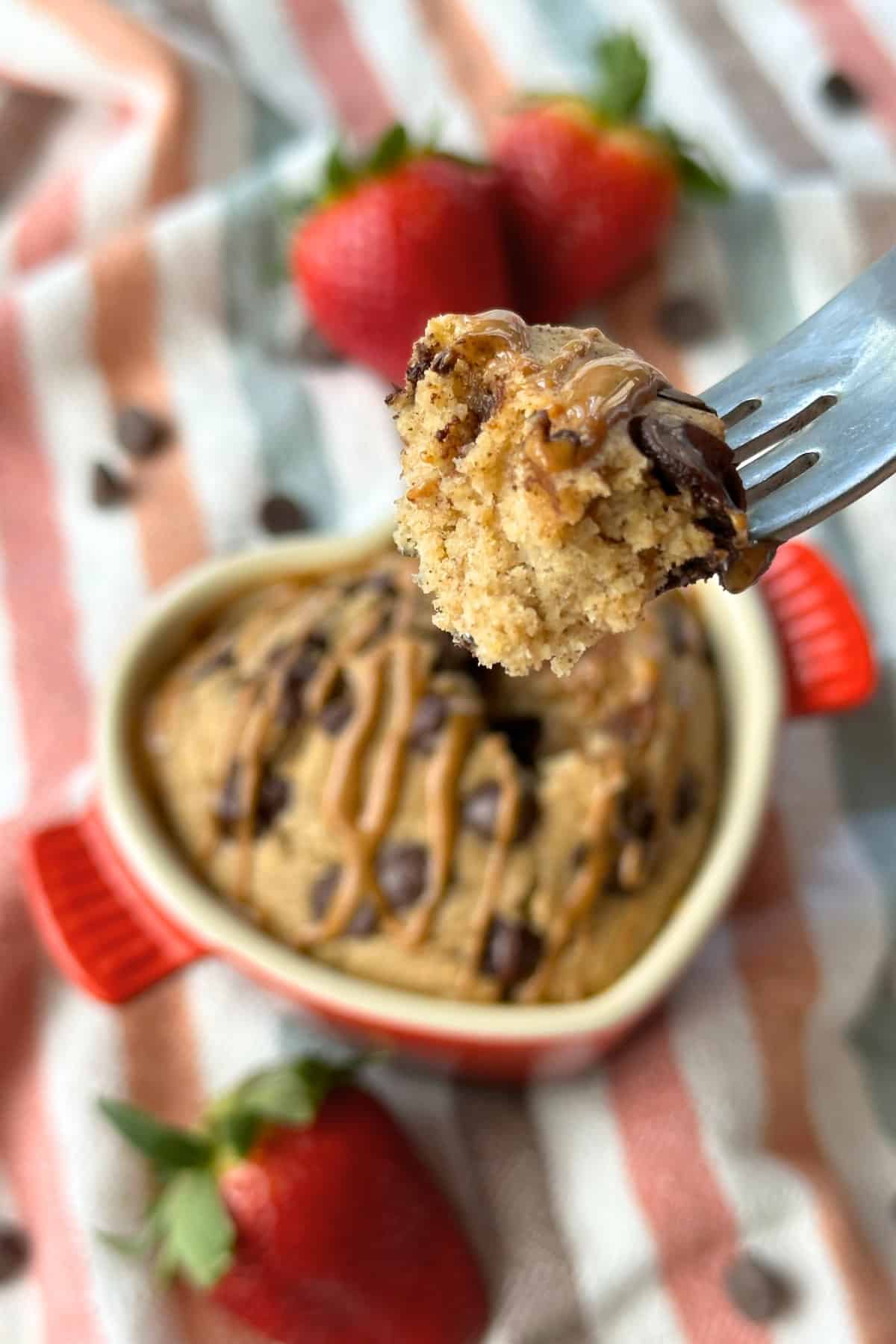 A fork with baked oatmeal on it. The background has the rest of the baked oats in a ramekin.