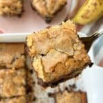 Slice of chocolate chip banana cake with more pieces in the background.
