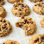 Mini chickpea chocolate chip cookies on a baking sheet with a bite taken out of one.