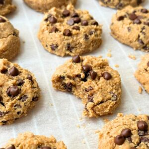 Mini chickpea chocolate chip cookies on a baking sheet with a bite taken out of one.