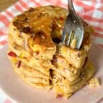 Stack of summer fruit pancakes with a fork taking out a slice.