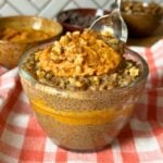 Pumpkin chia pudding in a glass bowl layered with pumpkin and topping with extra pumpkin and chopped nuts.