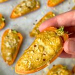 Mini pepper popper with baked tofu filling topped with crushed tortilla chips and red pepper flakes.