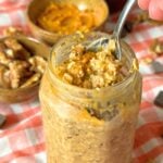 Jar of pumpkin spice overnight oats with a spoon and walnuts and chocolate chips.