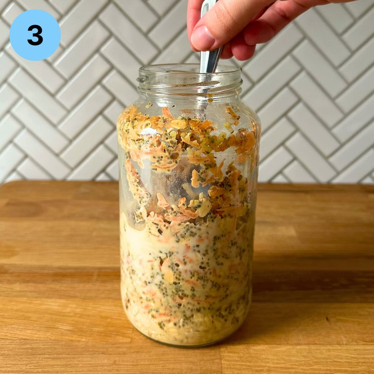 Mixing together the ingredients for overnight oatmeal in a glass jar with a spoon.