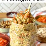 Carrot cake overnight oats in a glass jar with a spoon taking out some of the oatmeal, bowls of shredded carrot, walnuts, oats, and coconut are in the background; text reads "carrot cake overnight oats".