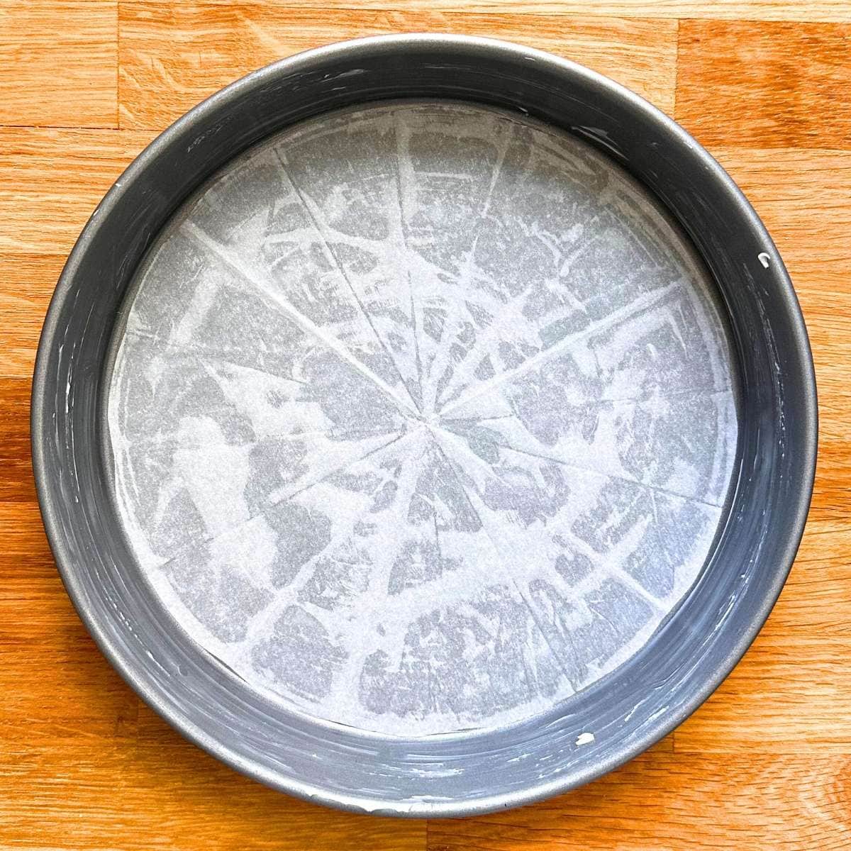 Prepared cake tin with butter and parchment paper.