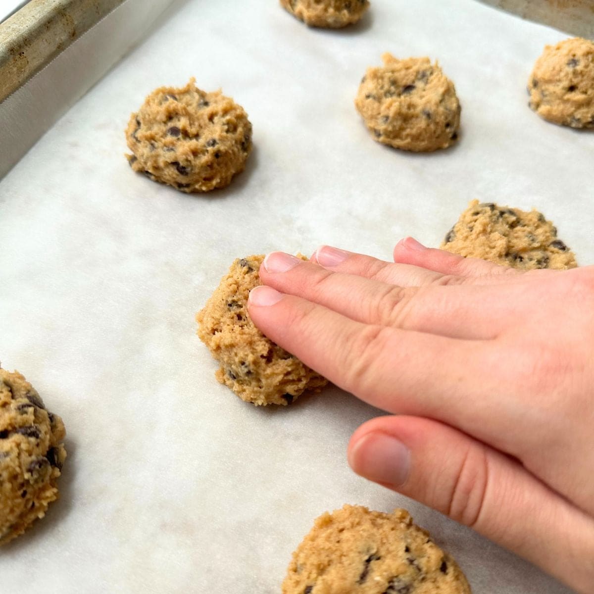 Flattening the cookies on a baking sheet.