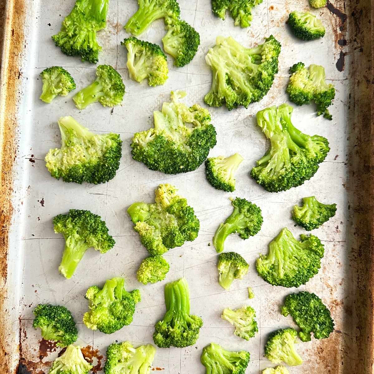 Smashed broccoli florets on a baking sheet.