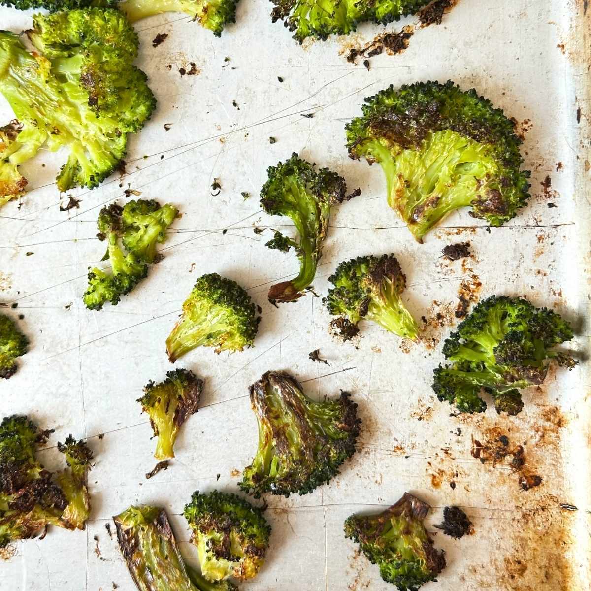 Roasted broccoli florets on a baking sheet with crispy edges.
