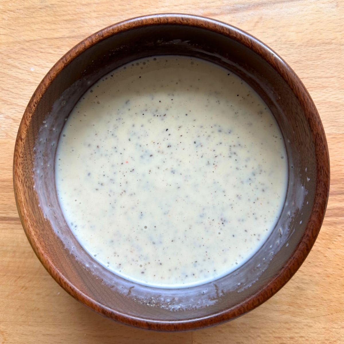 Creamy vegan coleslaw dressing made with silken tofu in a wooden bowl.