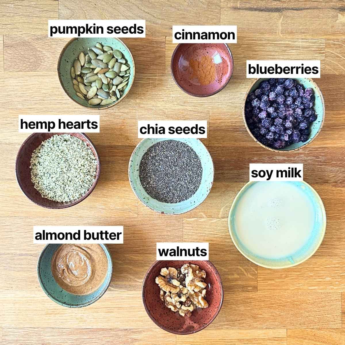 Ingredients needed for high protein chia seed pudding: pumpkin seeds, cinnamon, blueberries, hemp hearts, chia seeds, soy milk, almond butter, and walnuts.