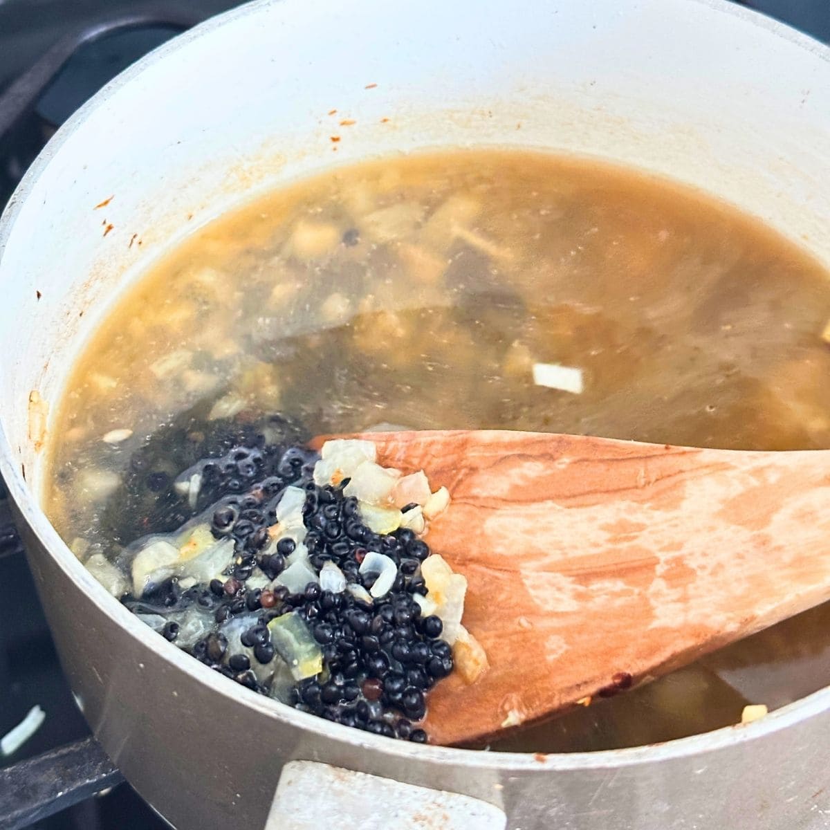 Black lentils and broth added to the sauteed onion and garlic.