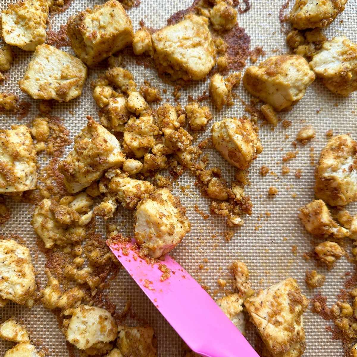 Nutritional yeast tofu partially baked, being flipped over.