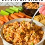 Buffalo chickpea salad in a bowl surrounded by carrot sticks, celery, and crackers.
