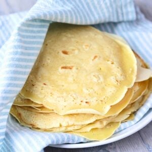 Chickpea flour tortillas stacked and wrapped in a blue and white cloth napkin.