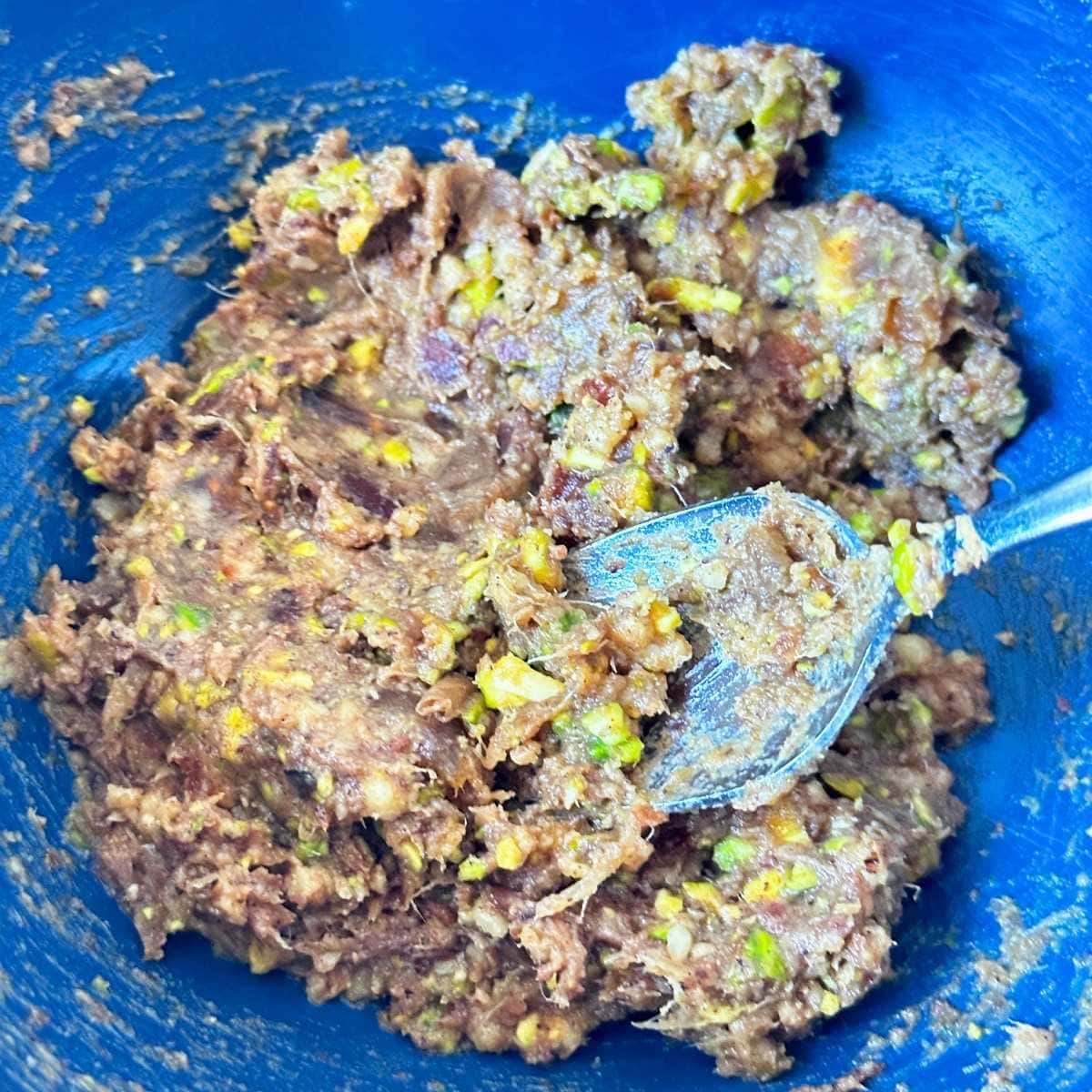 Dates, nuts, and spices mixed into a dough in a bowl.