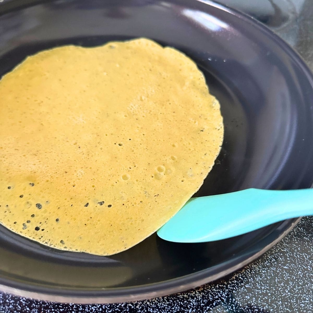 Edges of chickpea flour tortilla pulling up off the pan.
