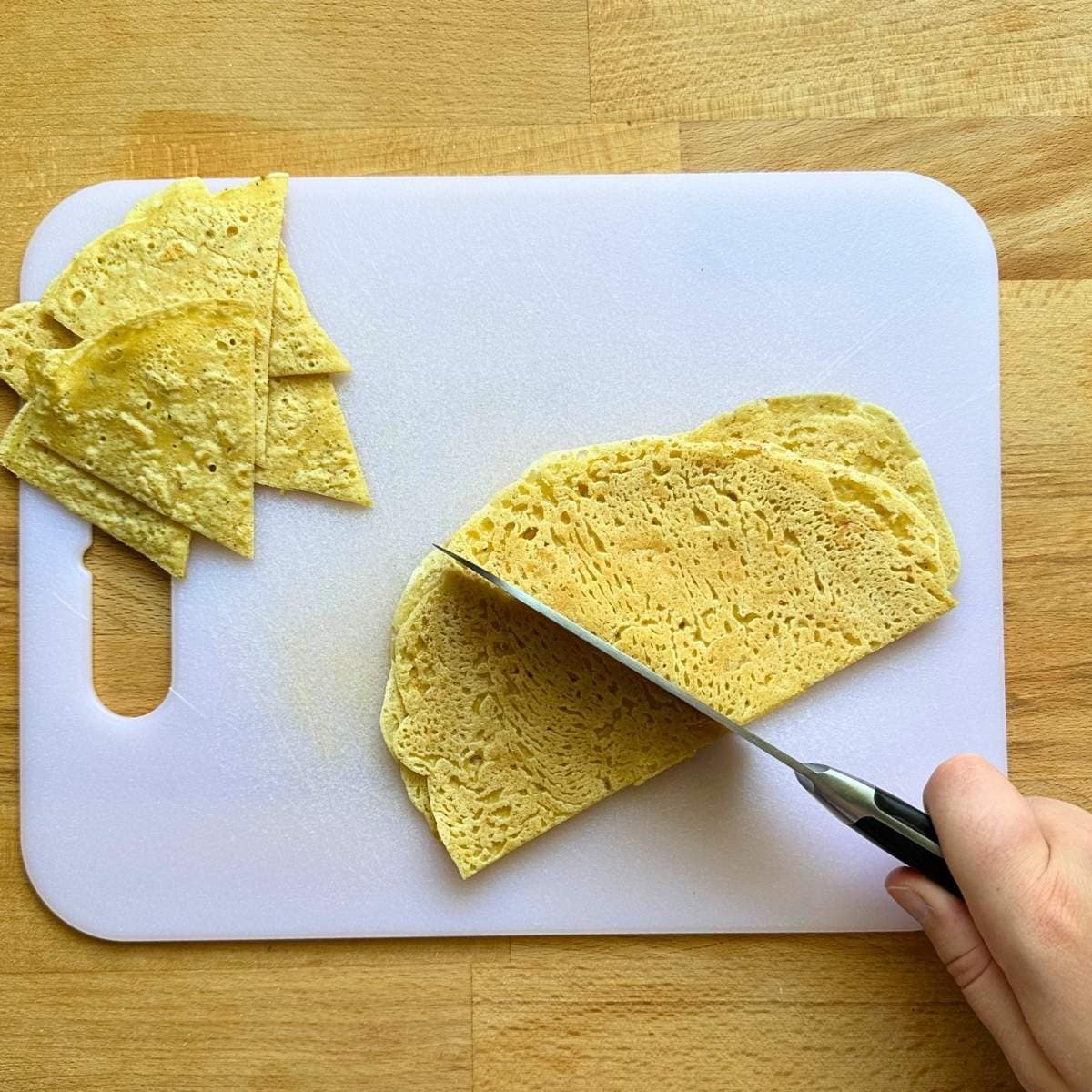 Chopping tortillas into triangles with a knife.