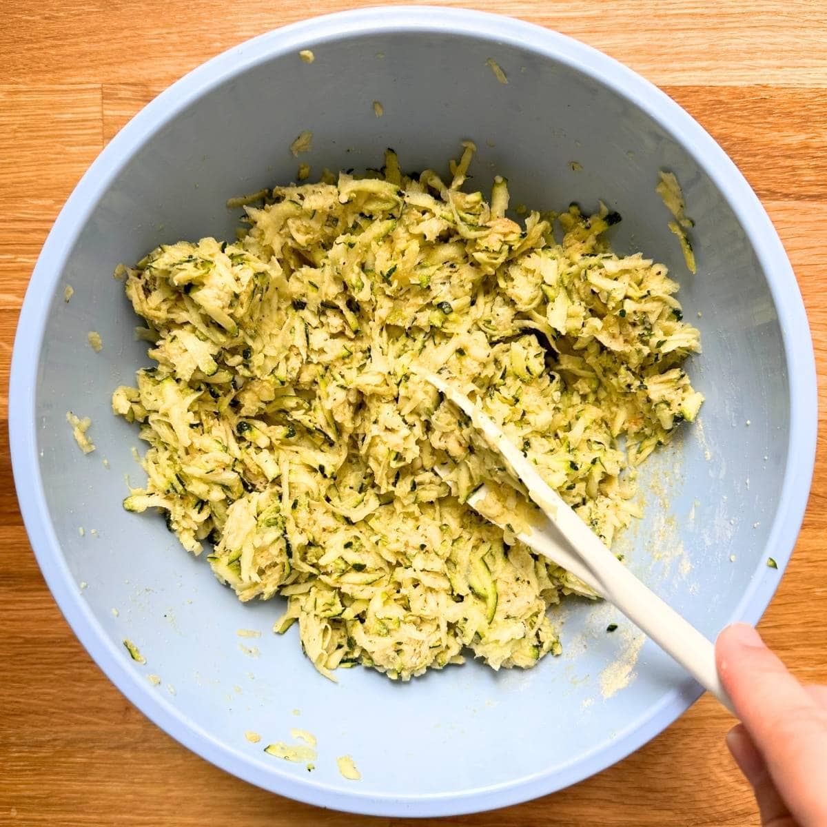 Zucchini fritter batter mixed in a bowl.
